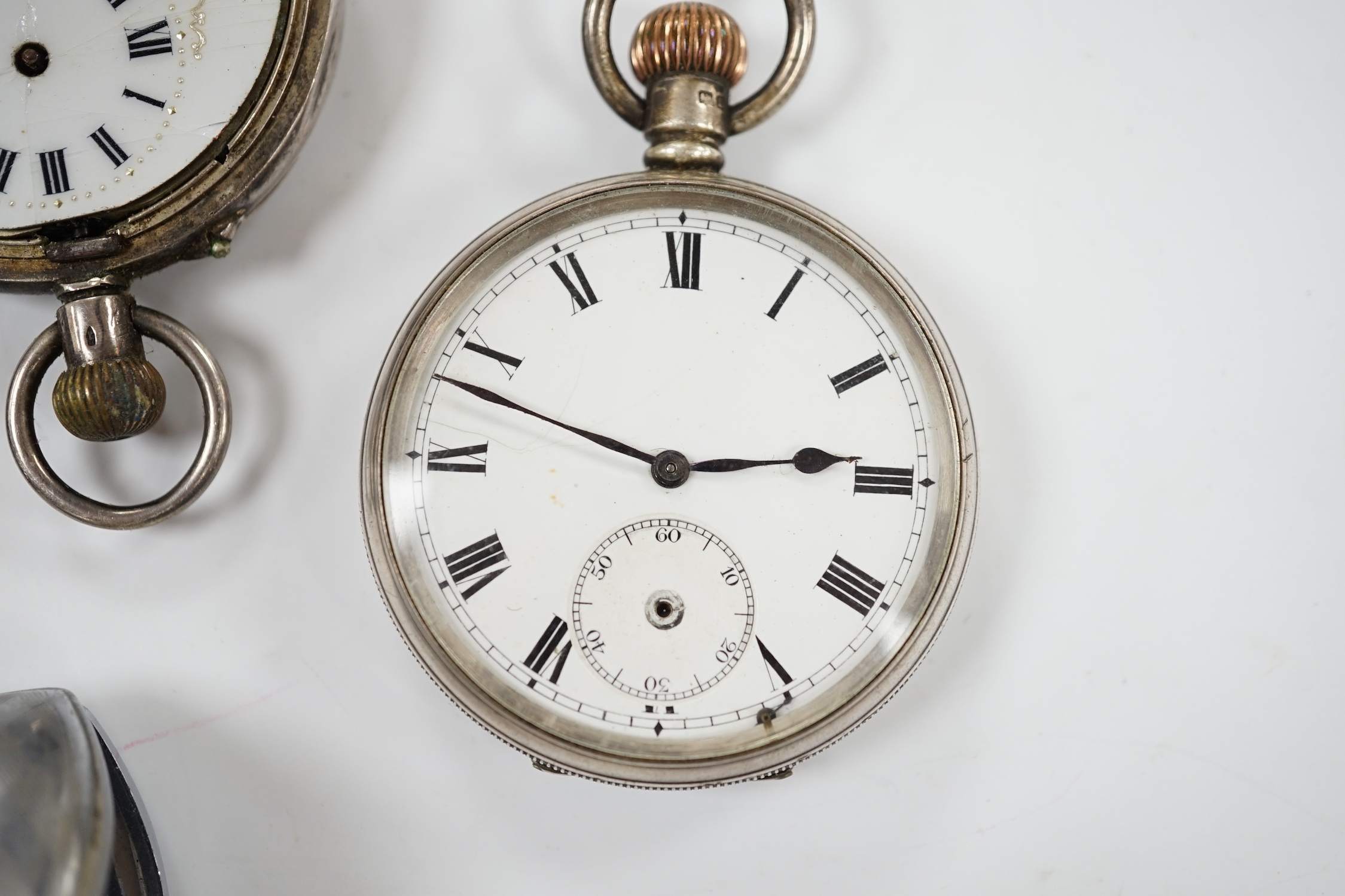Three silver pocket watches and a travel timepiece.